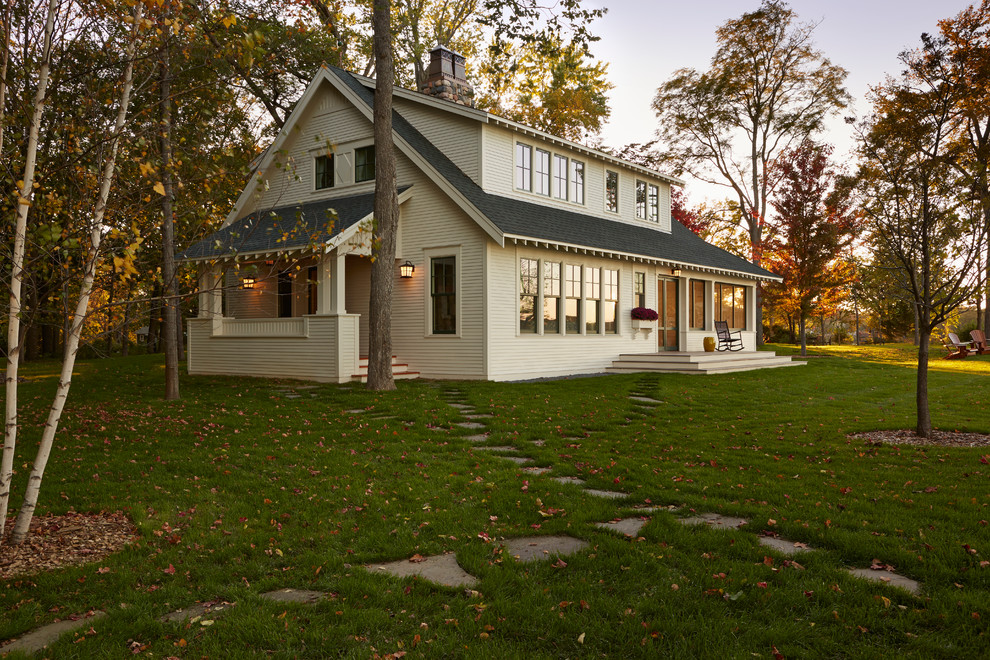 Imagen de fachada de casa blanca clásica de tamaño medio de dos plantas con tejado a dos aguas, revestimiento de madera y tejado de teja de madera
