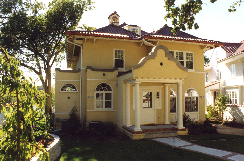 Dreistöckiges Mediterranes Haus mit Putzfassade, gelber Fassadenfarbe und Walmdach in Minneapolis