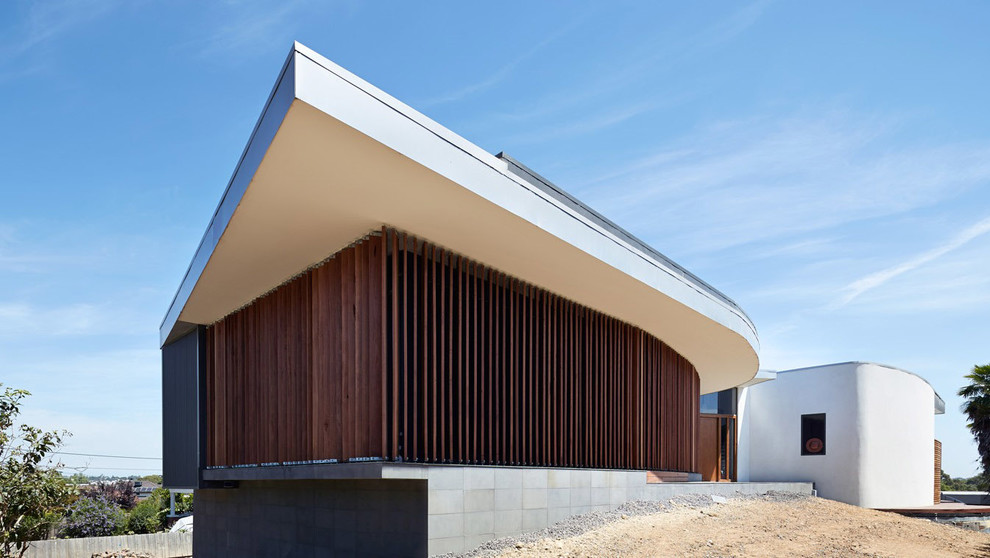 Exemple d'une grande façade de maison grise tendance en bois à niveaux décalés.