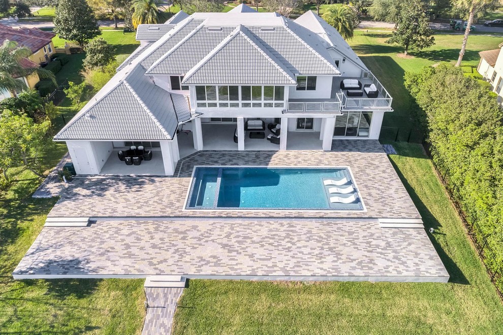 Diseño de fachada de casa blanca contemporánea grande de dos plantas con revestimiento de estuco, tejado a cuatro aguas y tejado de teja de barro