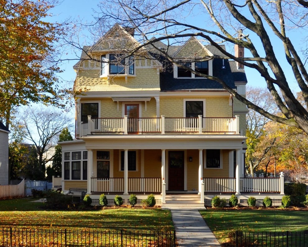 На фото: трехэтажный, деревянный, желтый частный загородный дом среднего размера в викторианском стиле с двускатной крышей и крышей из гибкой черепицы