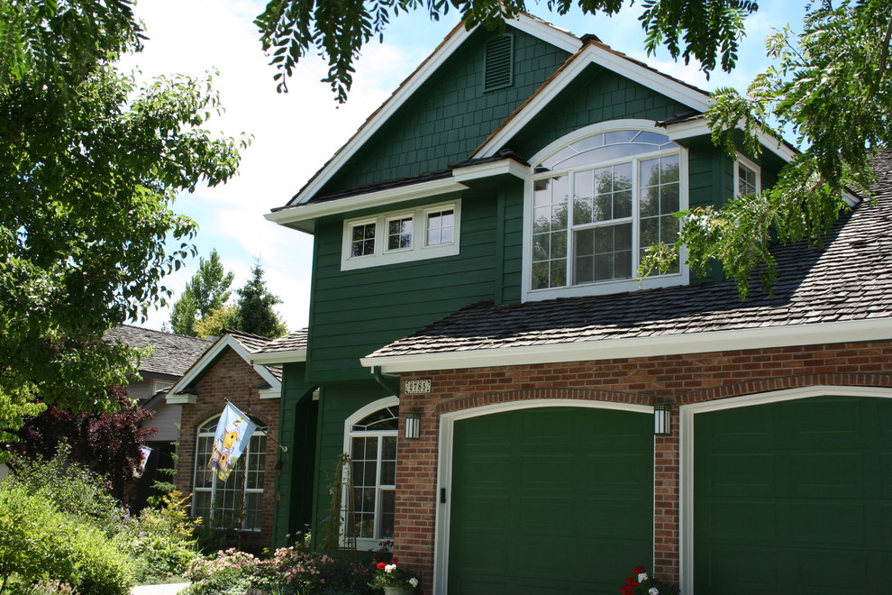 Ejemplo de fachada verde de estilo americano grande de dos plantas con revestimiento de ladrillo y tejado a cuatro aguas