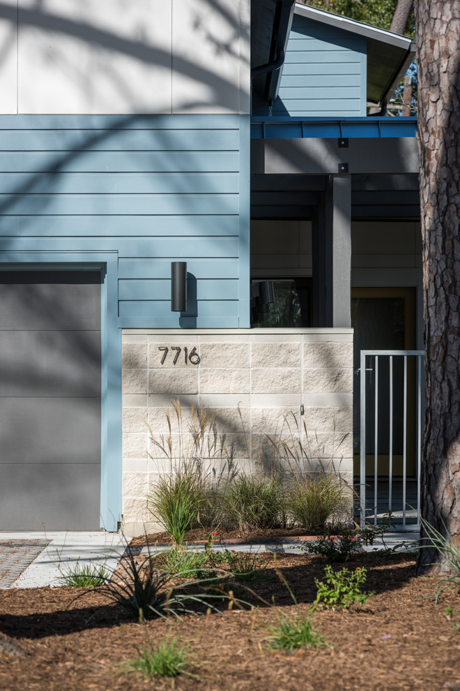 Réalisation d'une façade de maison bleue design en panneau de béton fibré de taille moyenne et à un étage avec un toit à deux pans et un toit en métal.