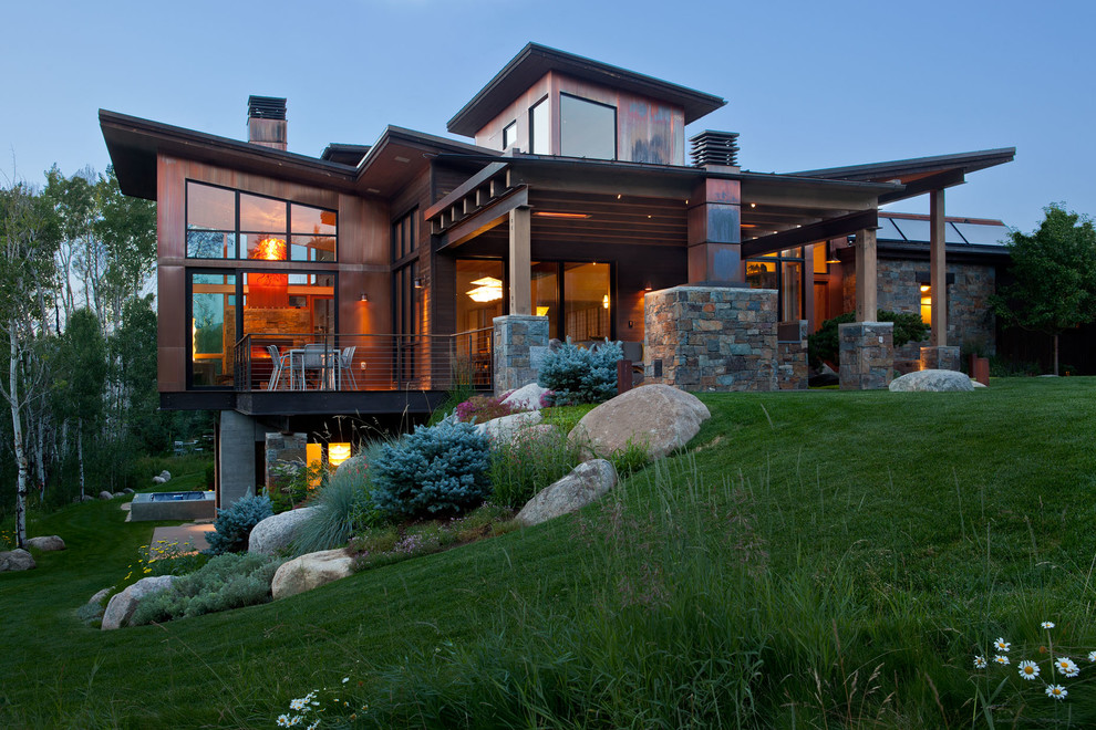 Photo of an expansive and brown rustic house exterior in Denver with three floors, mixed cladding and a lean-to roof.