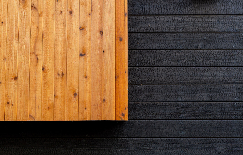 Modelo de fachada de casa negra minimalista grande de tres plantas con revestimiento de madera