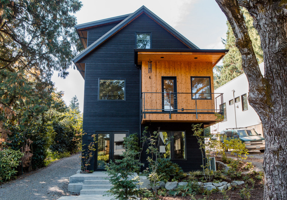 Réalisation d'une grande façade de maison noire minimaliste en bois à deux étages et plus.