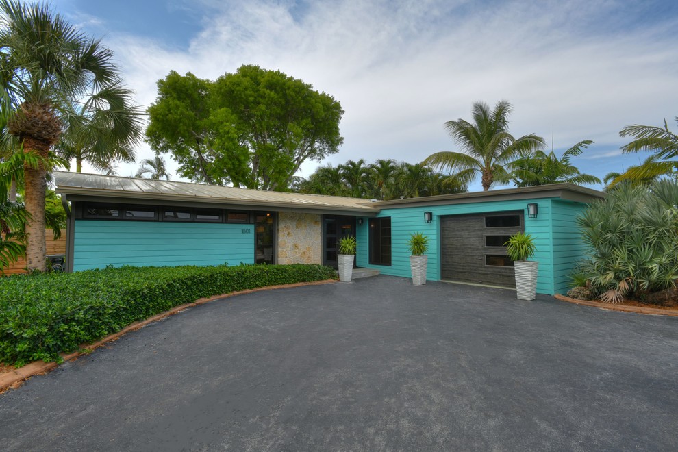 Mittelgroßes, Einstöckiges Mid-Century Einfamilienhaus mit Vinylfassade, blauer Fassadenfarbe, Flachdach und Blechdach in Miami