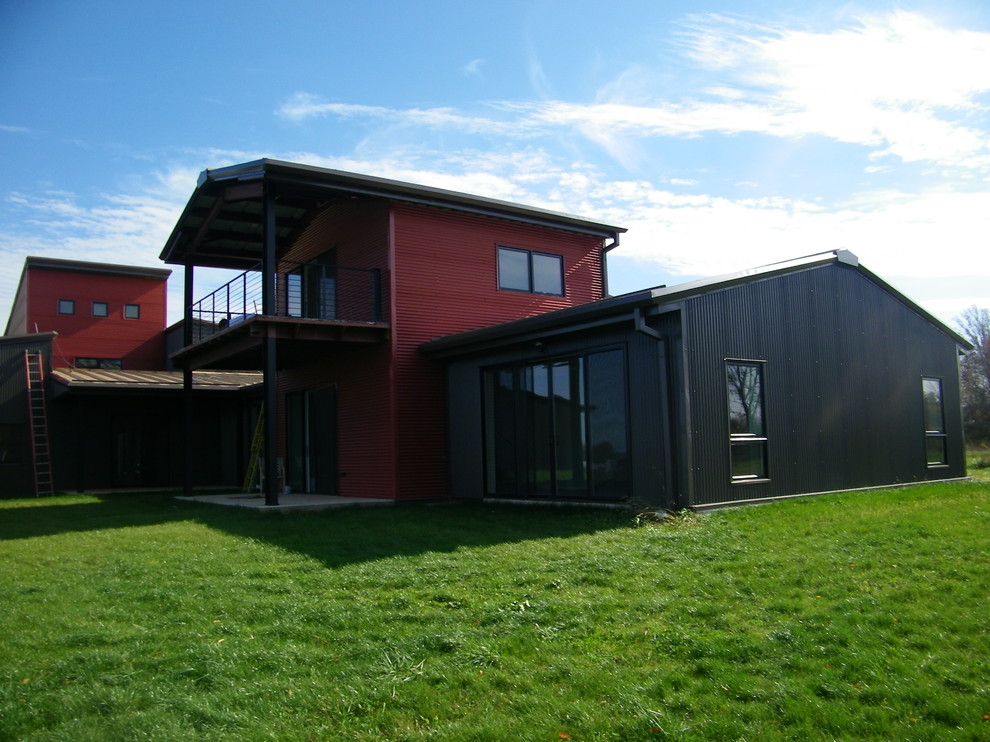 Immagine della facciata di una casa grande rossa industriale a tre piani con rivestimento in metallo e copertura in metallo o lamiera