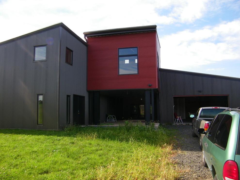 Réalisation d'une grande façade de maison métallique et rouge urbaine à deux étages et plus avec un toit en appentis et un toit en métal.
