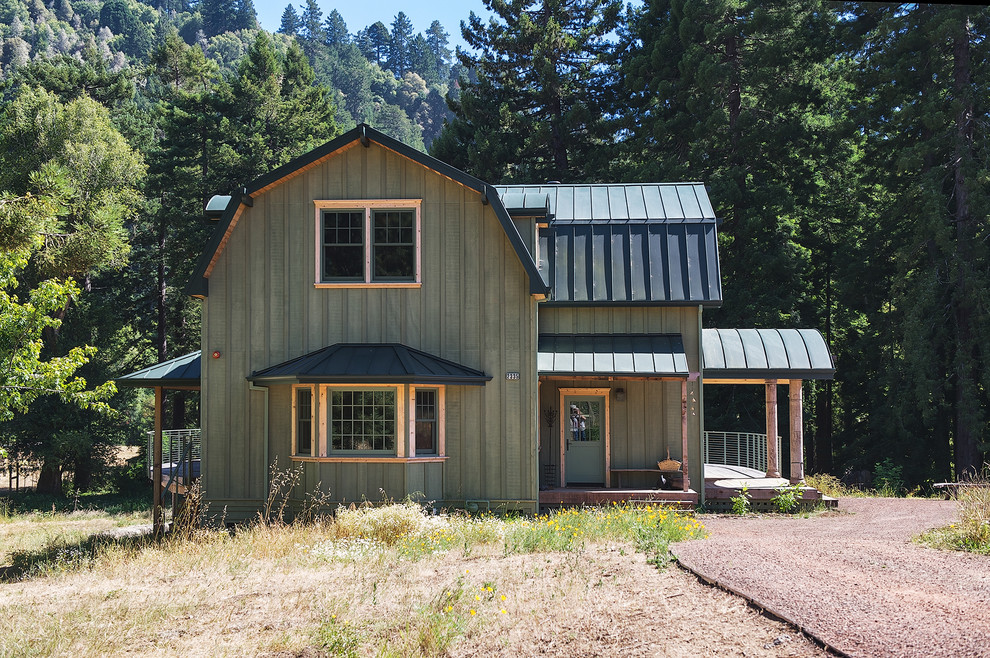 Foto della facciata di una casa verde country a due piani con rivestimento in legno e tetto a mansarda