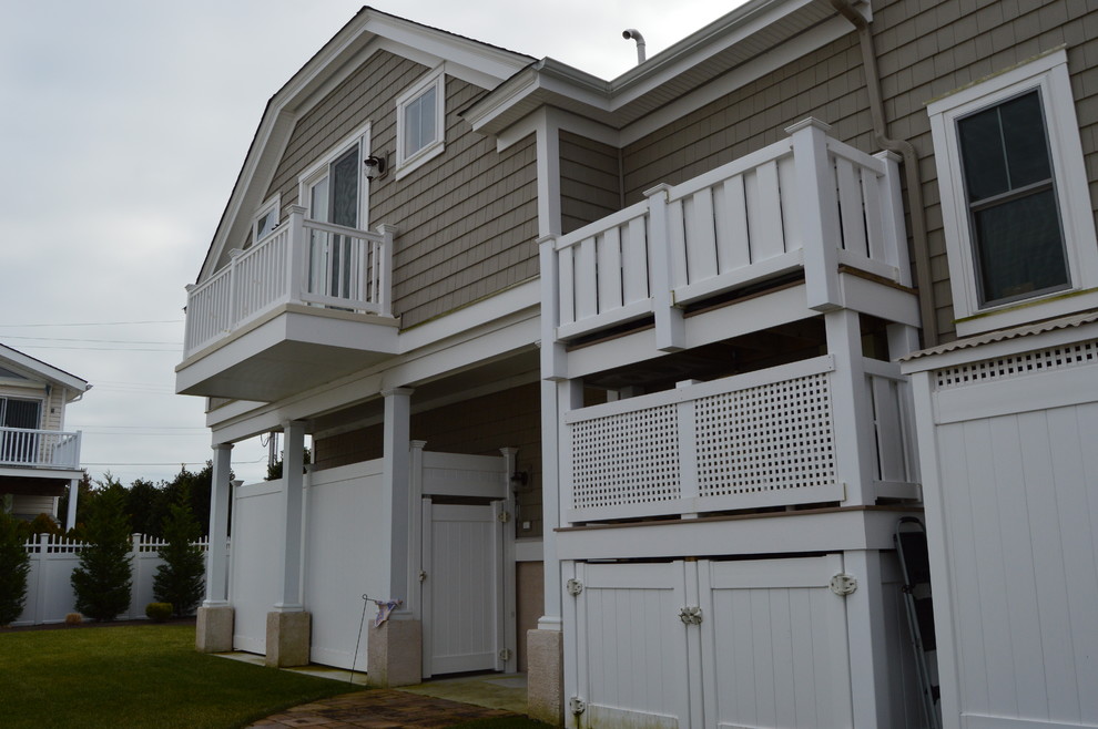 На фото: двухэтажный, бежевый дом в морском стиле с облицовкой из винила
