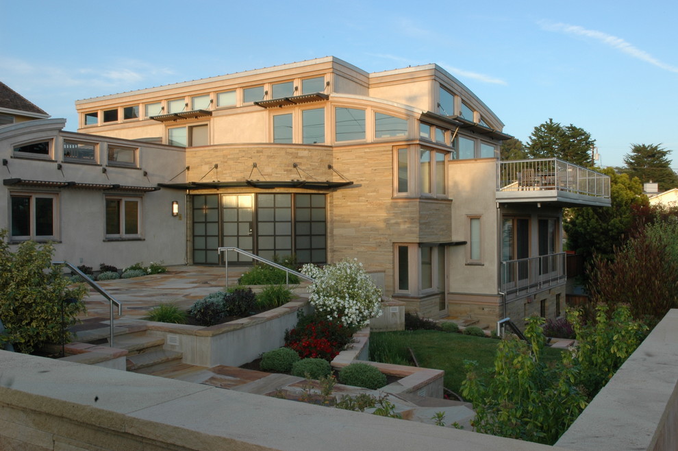 Immagine della facciata di una casa ampia beige contemporanea a tre piani con rivestimento in pietra e tetto piano