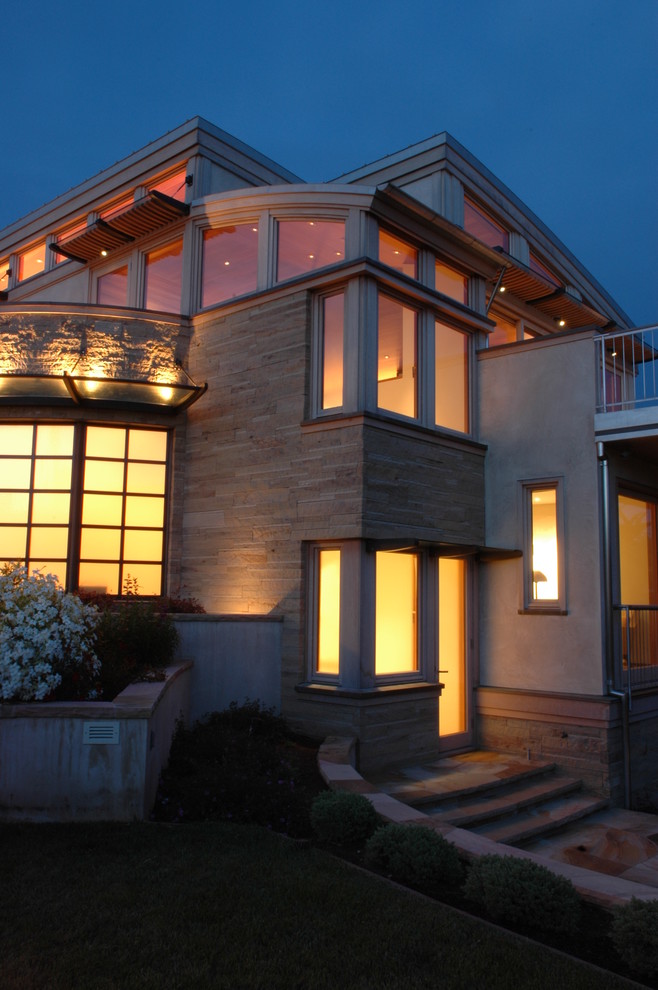 Пример оригинального дизайна: большой, трехэтажный, бежевый дом в современном стиле с облицовкой из камня и плоской крышей