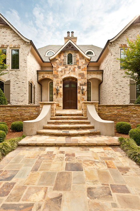 Foto della facciata di una casa ampia marrone classica a tre piani con rivestimento in pietra