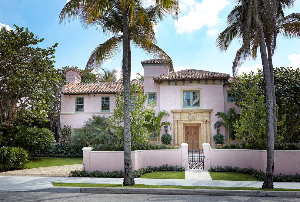 Réalisation d'une façade de maison rose méditerranéenne à un étage avec un toit à quatre pans et un toit en tuile.