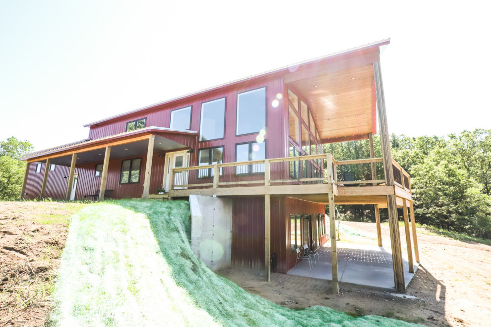 На фото: большой, двухэтажный, красный дом с облицовкой из металла и металлической крышей
