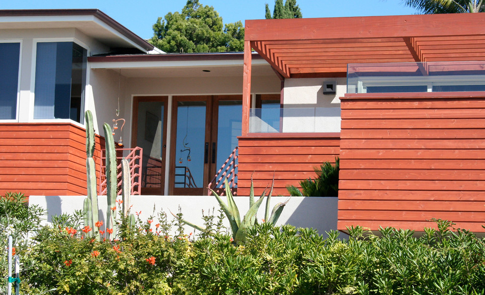 Réalisation d'une grande façade de maison rouge design en bois à un étage avec un toit à quatre pans.