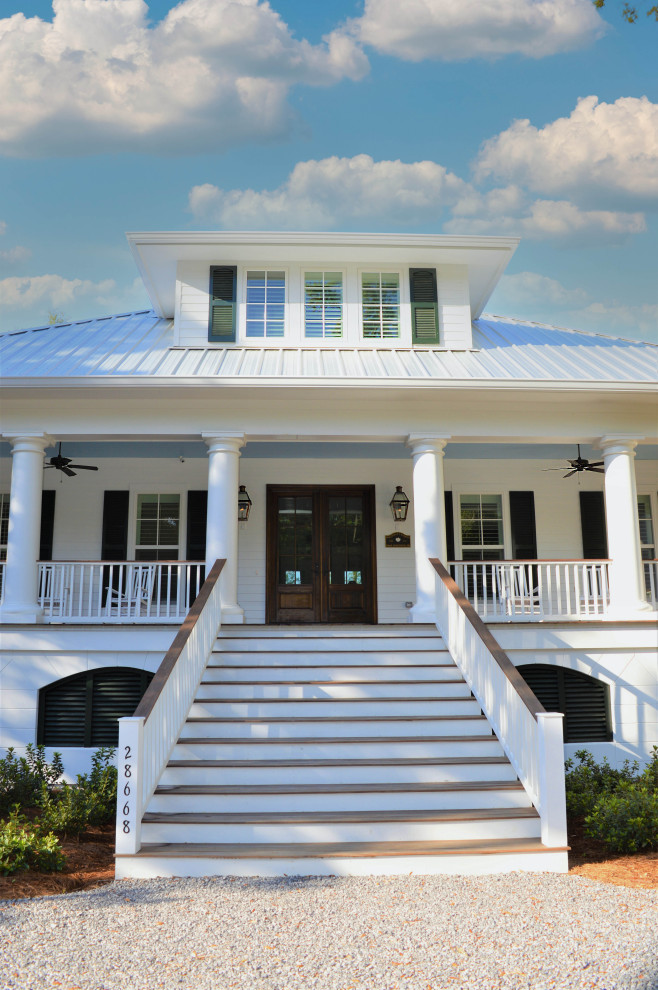 Esempio della facciata di una casa bianca stile marinaro a tre piani con rivestimento in legno, tetto a padiglione e copertura in metallo o lamiera