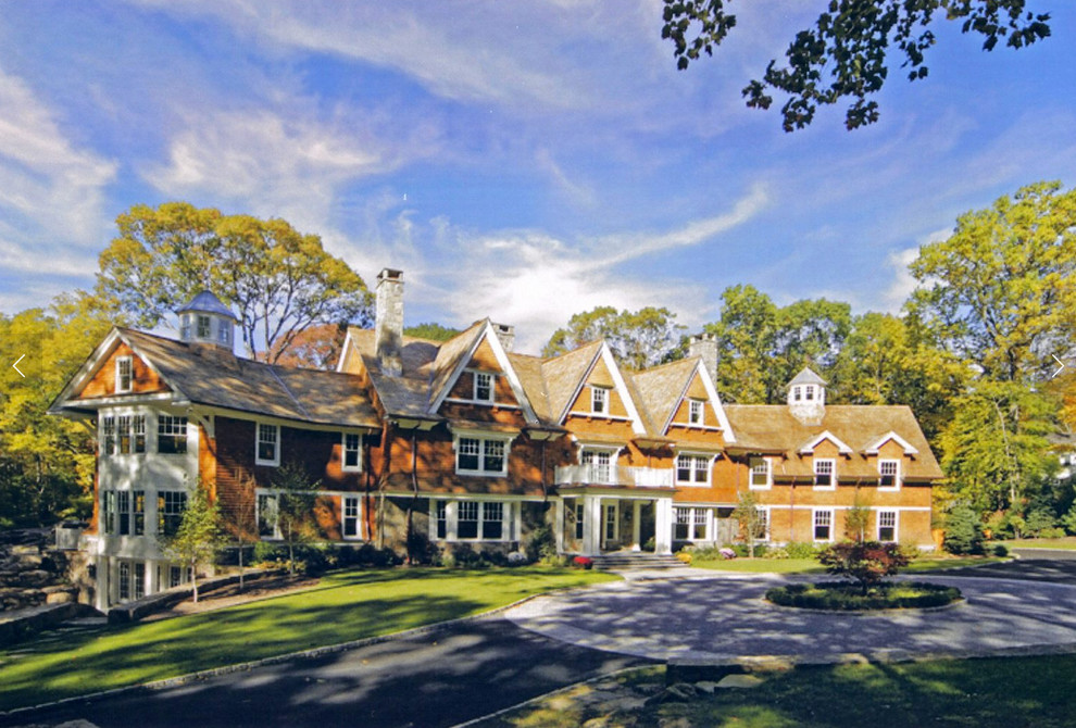 На фото: огромный, трехэтажный, деревянный, коричневый дом в классическом стиле с полувальмовой крышей с