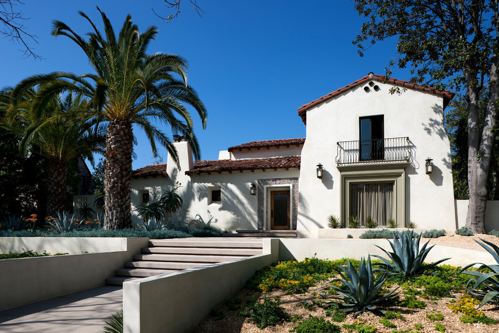 Diseño de fachada de casa blanca mediterránea de tamaño medio de dos plantas con revestimiento de estuco, tejado a dos aguas y tejado de teja de barro