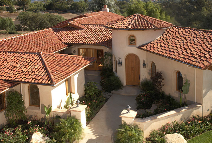 Diseño de fachada de casa beige mediterránea de tamaño medio de dos plantas con revestimiento de estuco, tejado a cuatro aguas y tejado de teja de barro