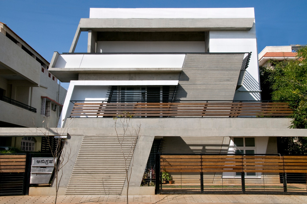This is an example of an expansive and white contemporary concrete house exterior in Bengaluru with three floors.