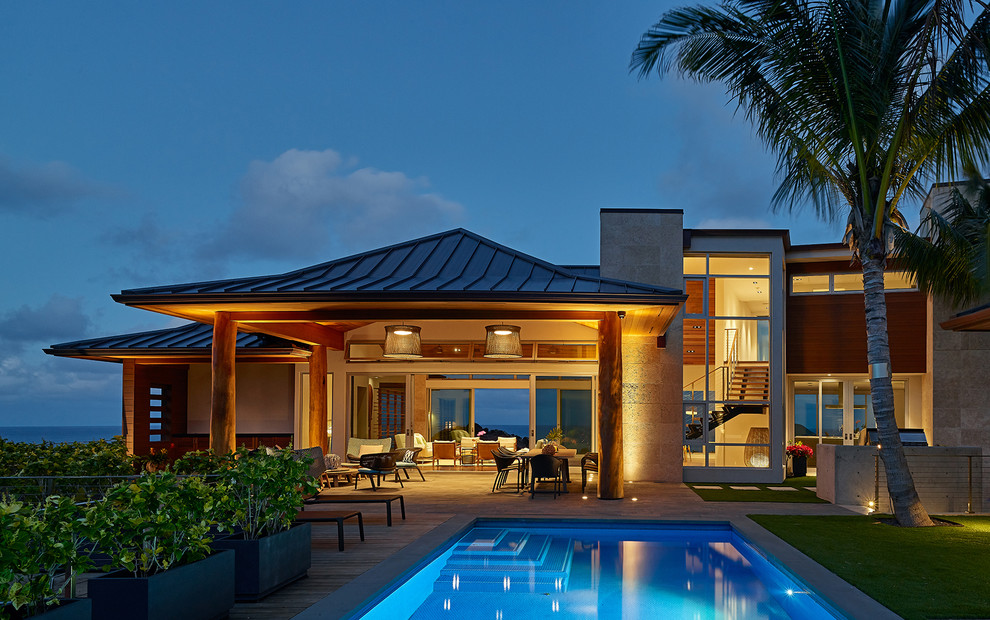 Bild på ett stort tropiskt beige hus, med allt i ett plan, stuckatur, valmat tak och tak i metall