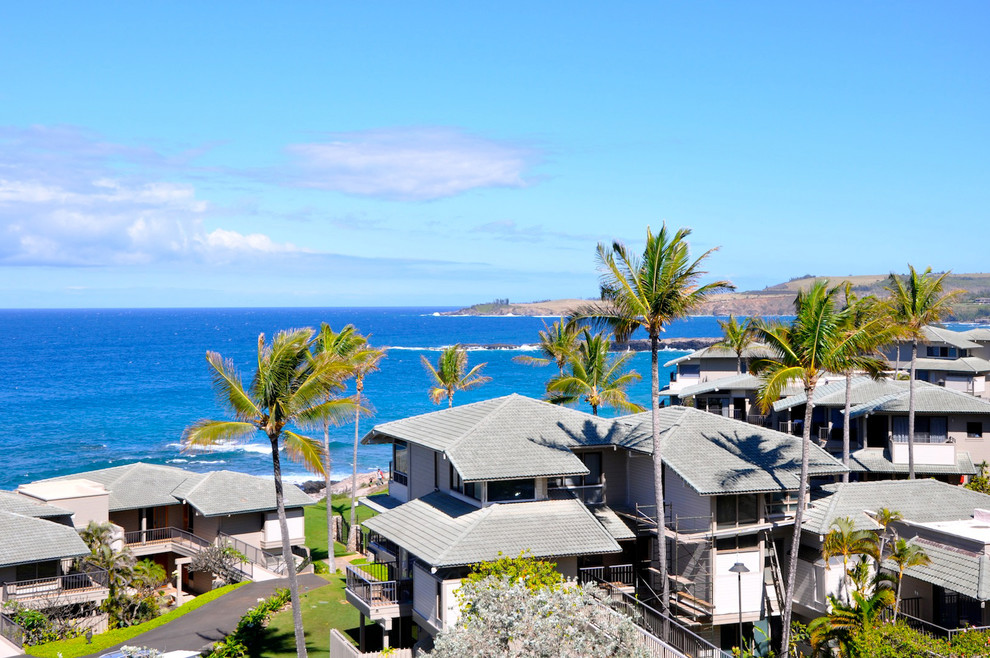 ハワイにあるラグジュアリーな巨大なトロピカルスタイルのおしゃれな家の外観 (漆喰サイディング、タウンハウス) の写真