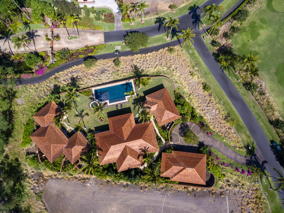 This is an example of a large and beige world-inspired bungalow render house exterior in Hawaii.