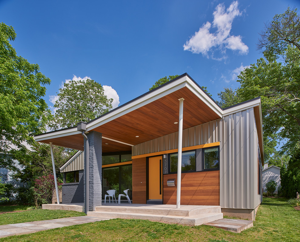 Ejemplo de fachada de casa gris retro de tamaño medio de una planta con revestimientos combinados y tejado a dos aguas