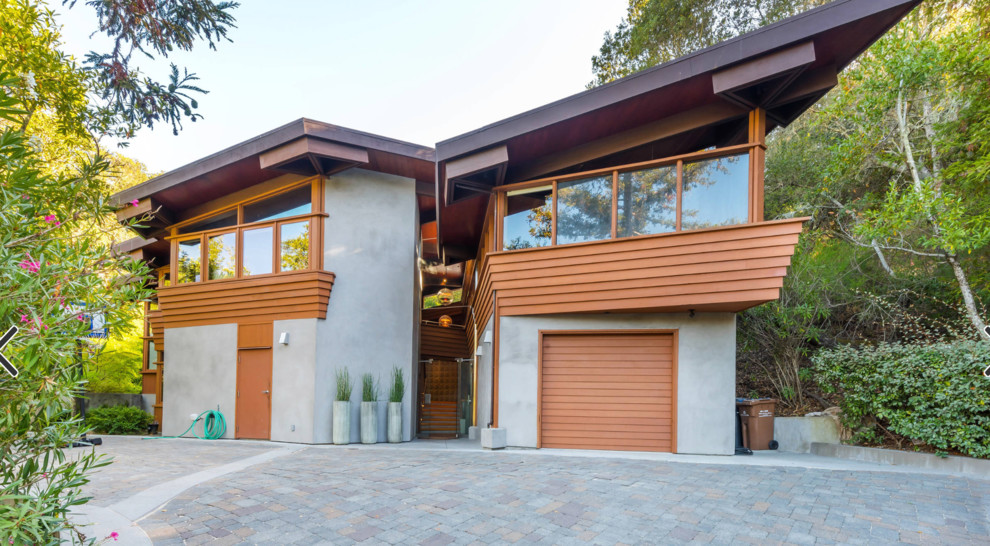 Cette image montre une façade de maison grise chalet à un étage avec un revêtement mixte et un toit en appentis.