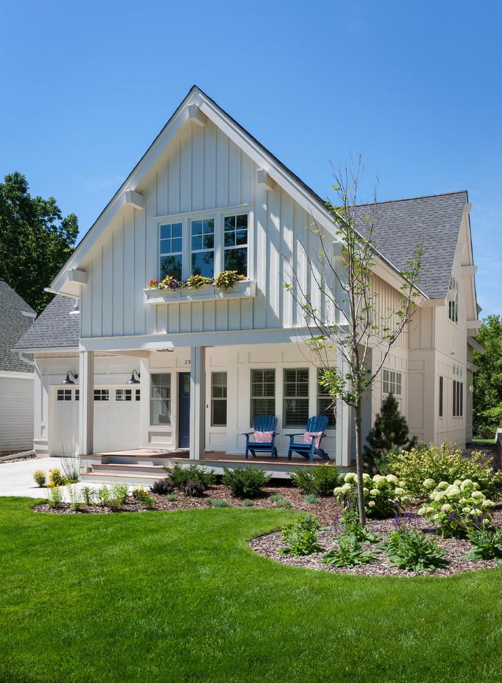 На фото: деревянный, белый дом среднего размера в классическом стиле с двускатной крышей с