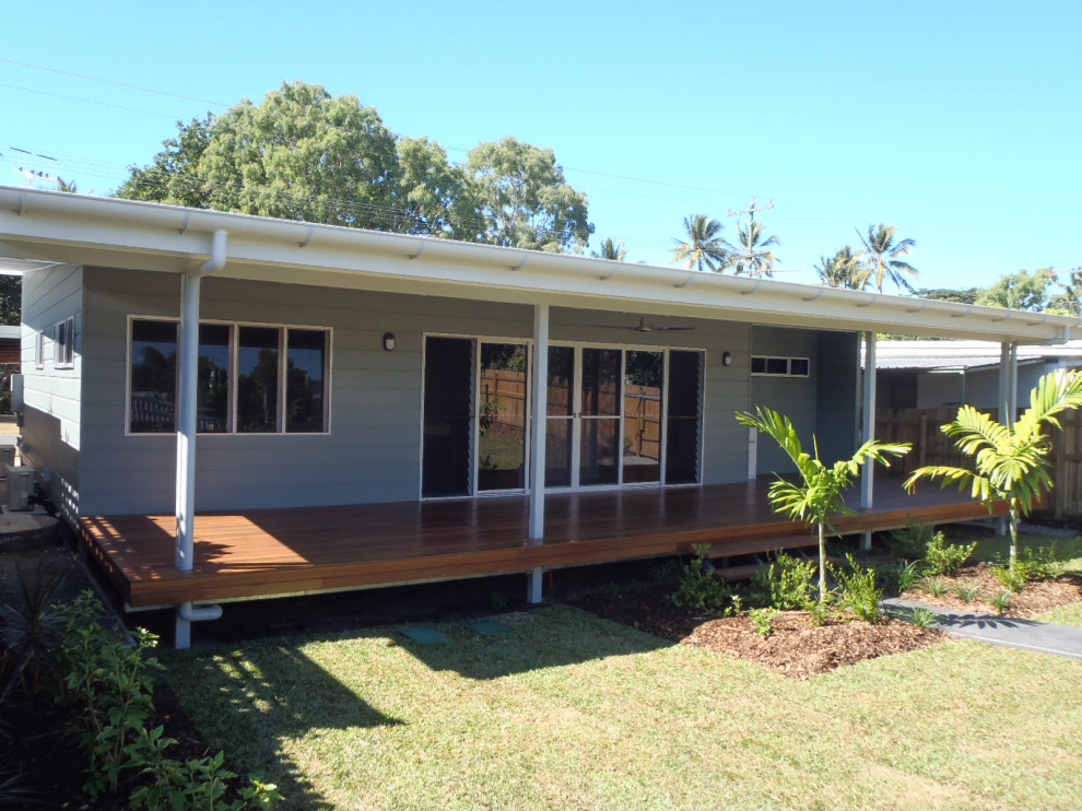 Gey nautical bungalow detached house in Cairns with wood cladding, a flat roof and a metal roof.