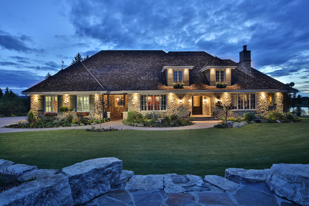 Inspiration for an expansive and gey rustic bungalow house exterior in Calgary with stone cladding.