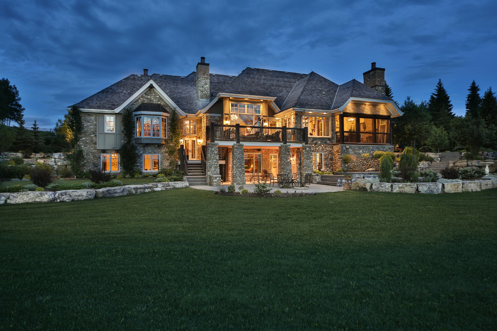 Expansive and gey rustic bungalow house exterior in Calgary with stone cladding.