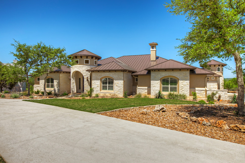 Mid-sized tuscan beige two-story stone house exterior photo in Austin with a hip roof and a metal roof