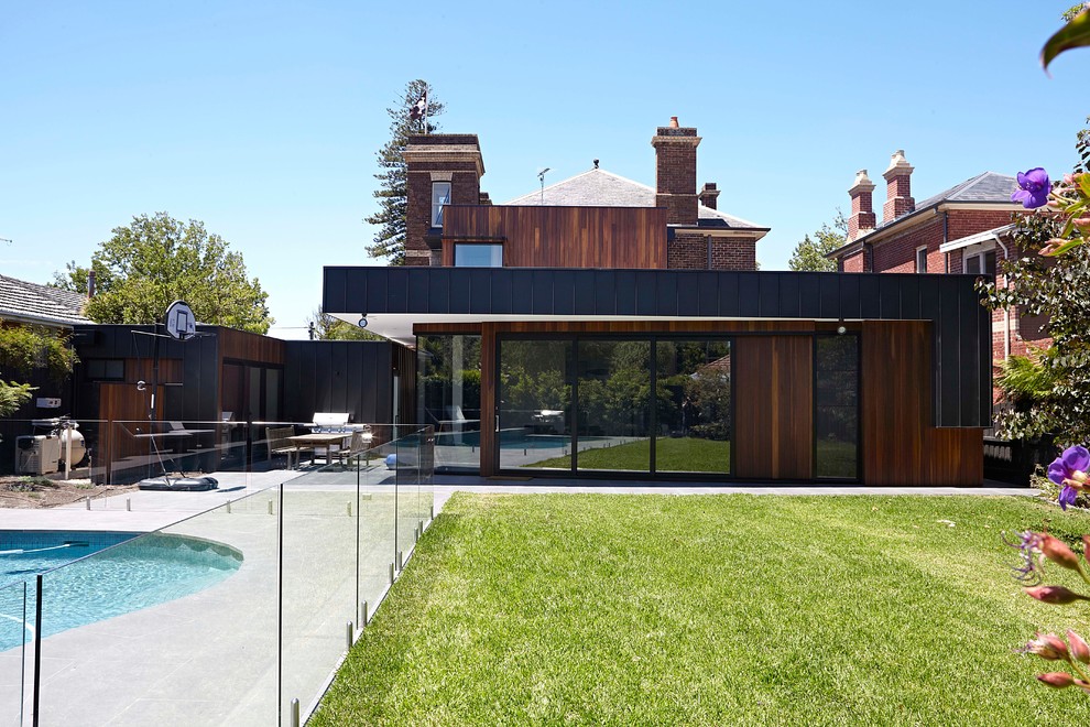 Inspiration pour une grande façade de maison marron design en bois à un étage avec un toit plat et un toit en métal.