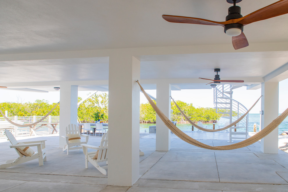 Large beach style blue three-story concrete exterior home photo in Miami with a metal roof