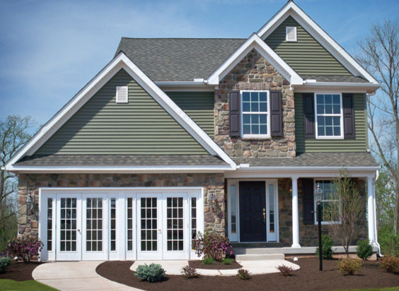 Cette image montre une façade de maison verte traditionnelle en pierre de taille moyenne et à un étage avec un toit à quatre pans.