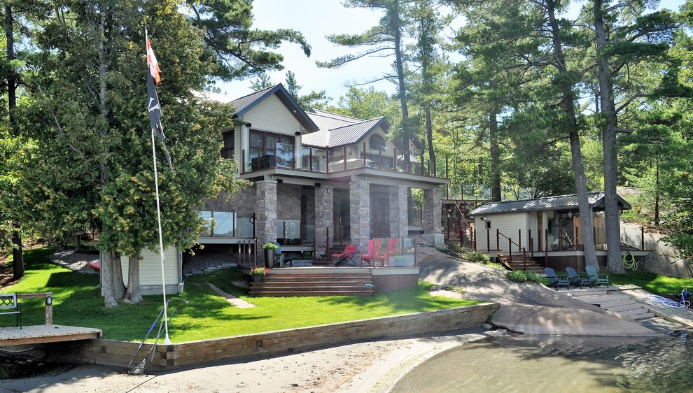 Cette photo montre une grande façade de maison grise tendance en bois à un étage avec un toit à deux pans.