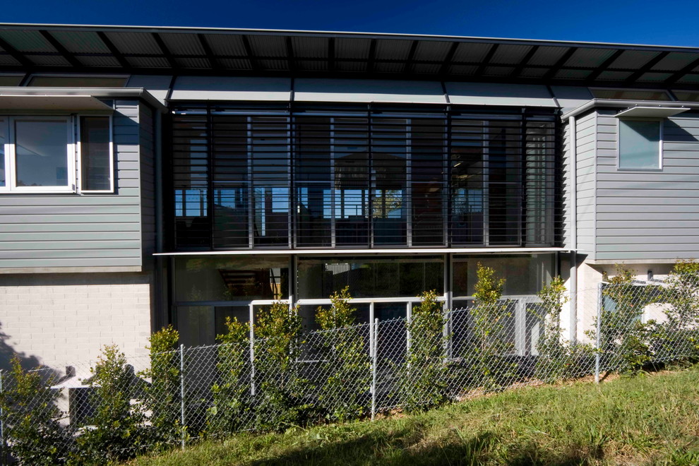 Inspiration pour une façade de maison métallique et grise minimaliste à un étage avec un toit plat.