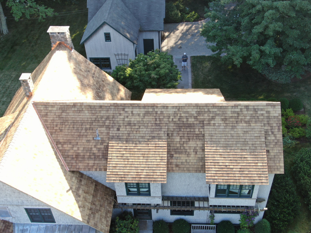 Modelo de fachada de casa beige campestre grande de tres plantas con revestimiento de madera, tejado a dos aguas y tejado de teja de madera