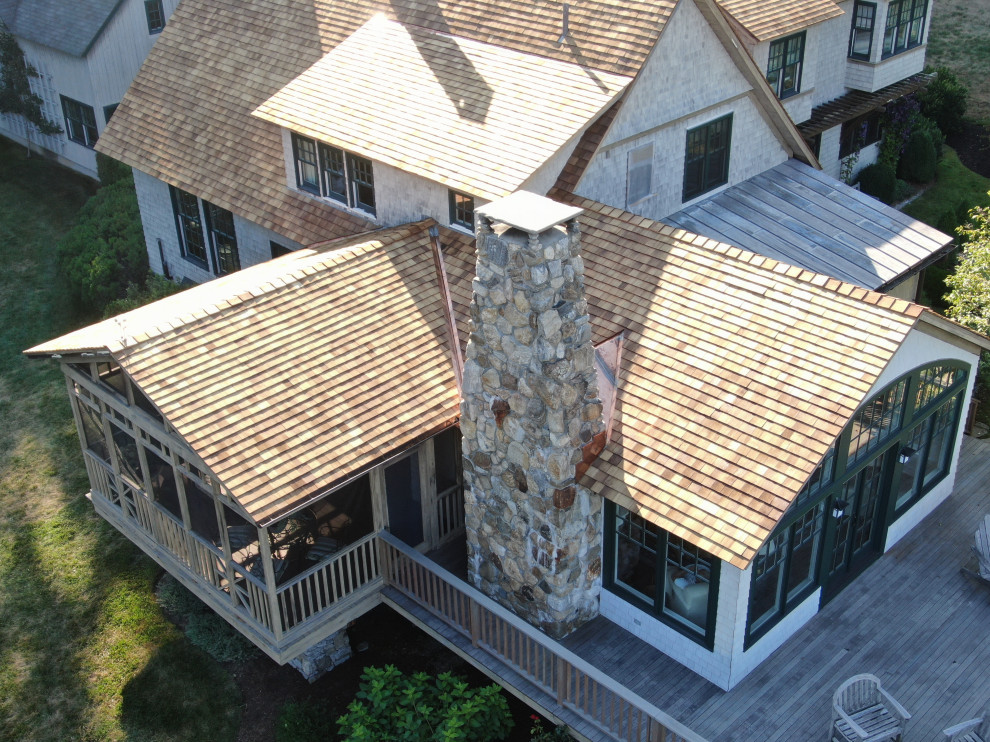 Idee per la villa grande beige country a tre piani con rivestimento in legno, tetto a capanna e copertura a scandole