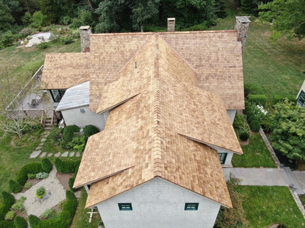 Modelo de fachada de casa beige campestre grande de tres plantas con revestimiento de madera, tejado a dos aguas y tejado de teja de madera