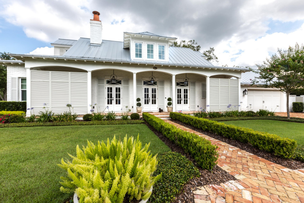 This is an example of a white classic two floor brick detached house in Orlando with a metal roof.