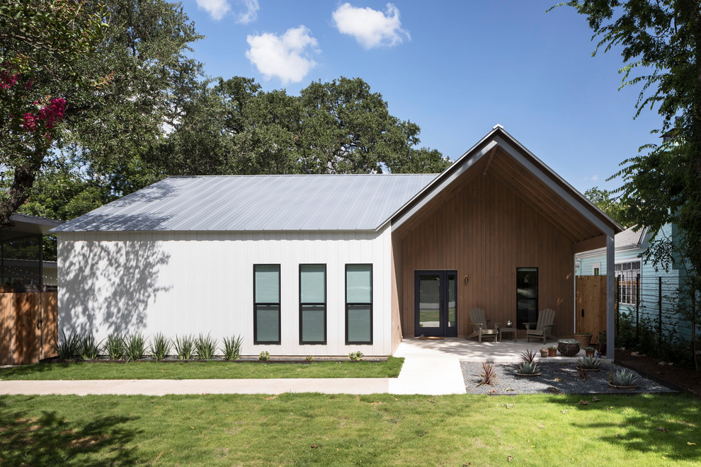 Aménagement d'une façade de maison blanche campagne en bois de plain-pied avec un toit à deux pans et un toit en métal.