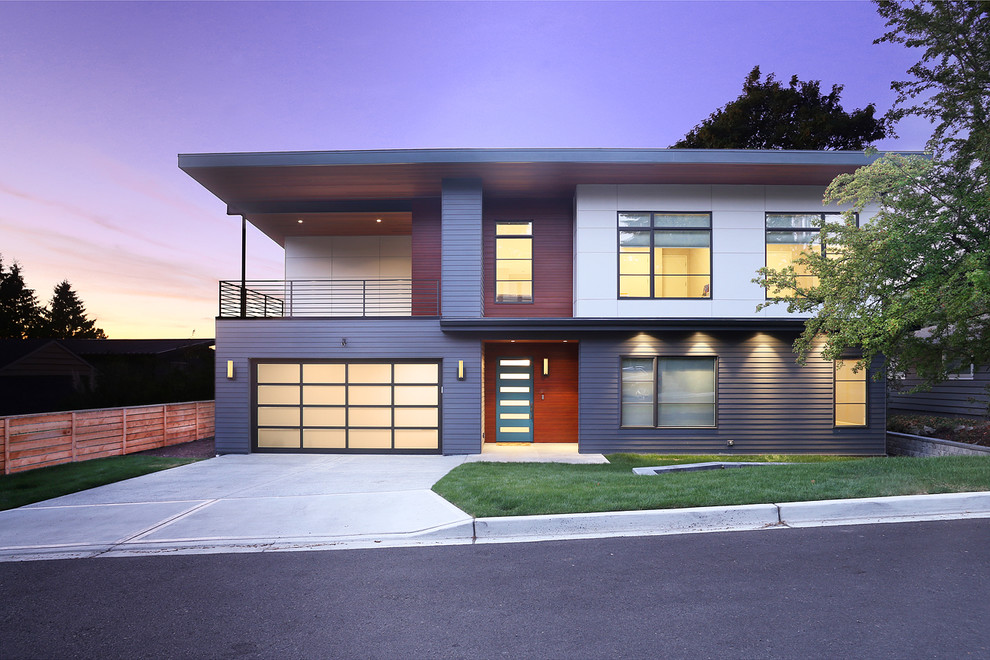Cette image montre une grande façade de maison bleue design à un étage avec un revêtement mixte et un toit plat.