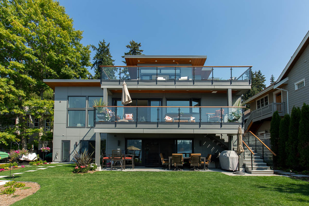 Mittelgroßes, Dreistöckiges Modernes Einfamilienhaus mit Faserzement-Fassade, grauer Fassadenfarbe, Pultdach und Blechdach in Seattle