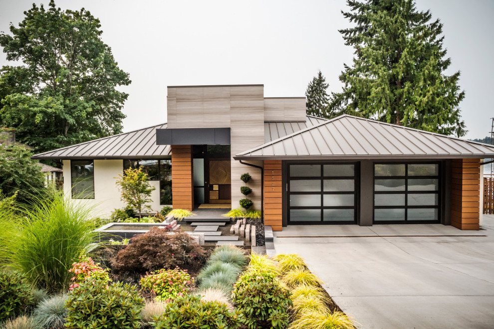 Cette image montre une façade de maison beige design de plain-pied avec un revêtement mixte, un toit à quatre pans, un toit en métal et un toit gris.