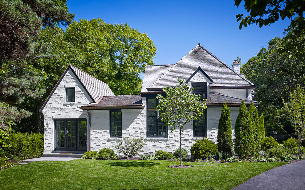 Imagen de fachada blanca tradicional grande de dos plantas con revestimiento de ladrillo y tejado a dos aguas
